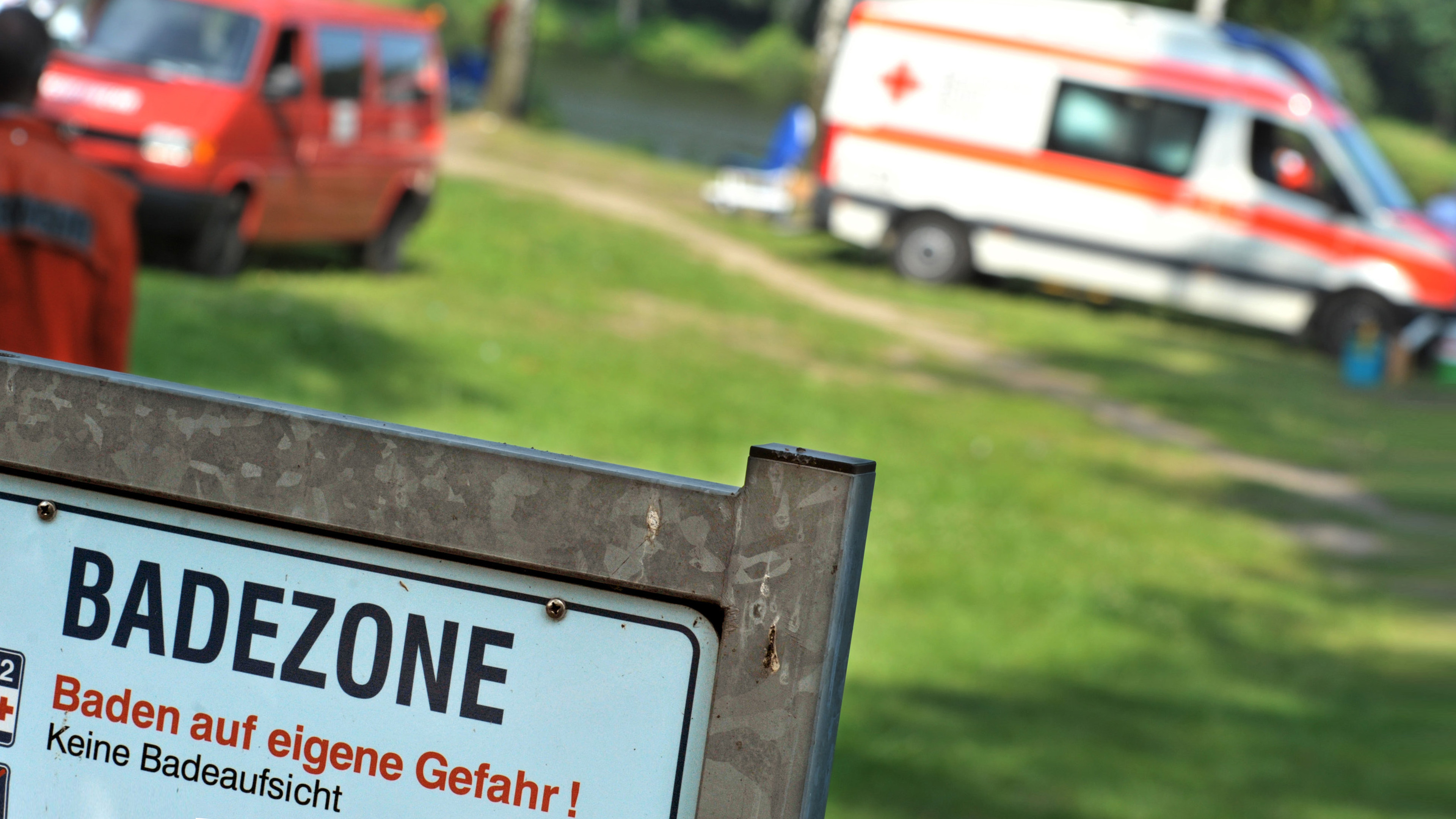 Rettungskräfte hinter einem Schild Badezone