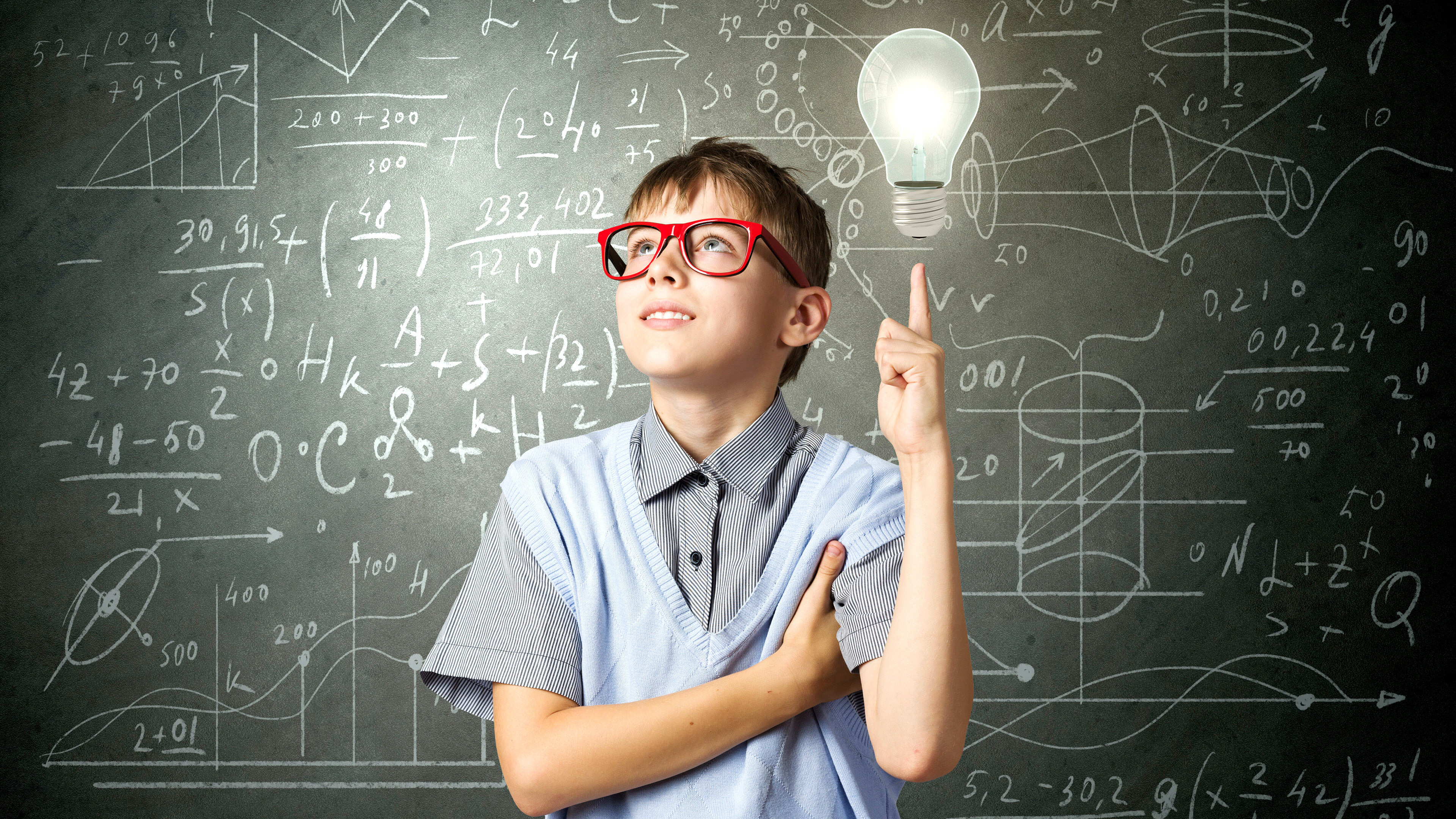 Junge mit Brille steht symbolisch vor einer Tafel mit mathematischen Formeln, Glühbirne