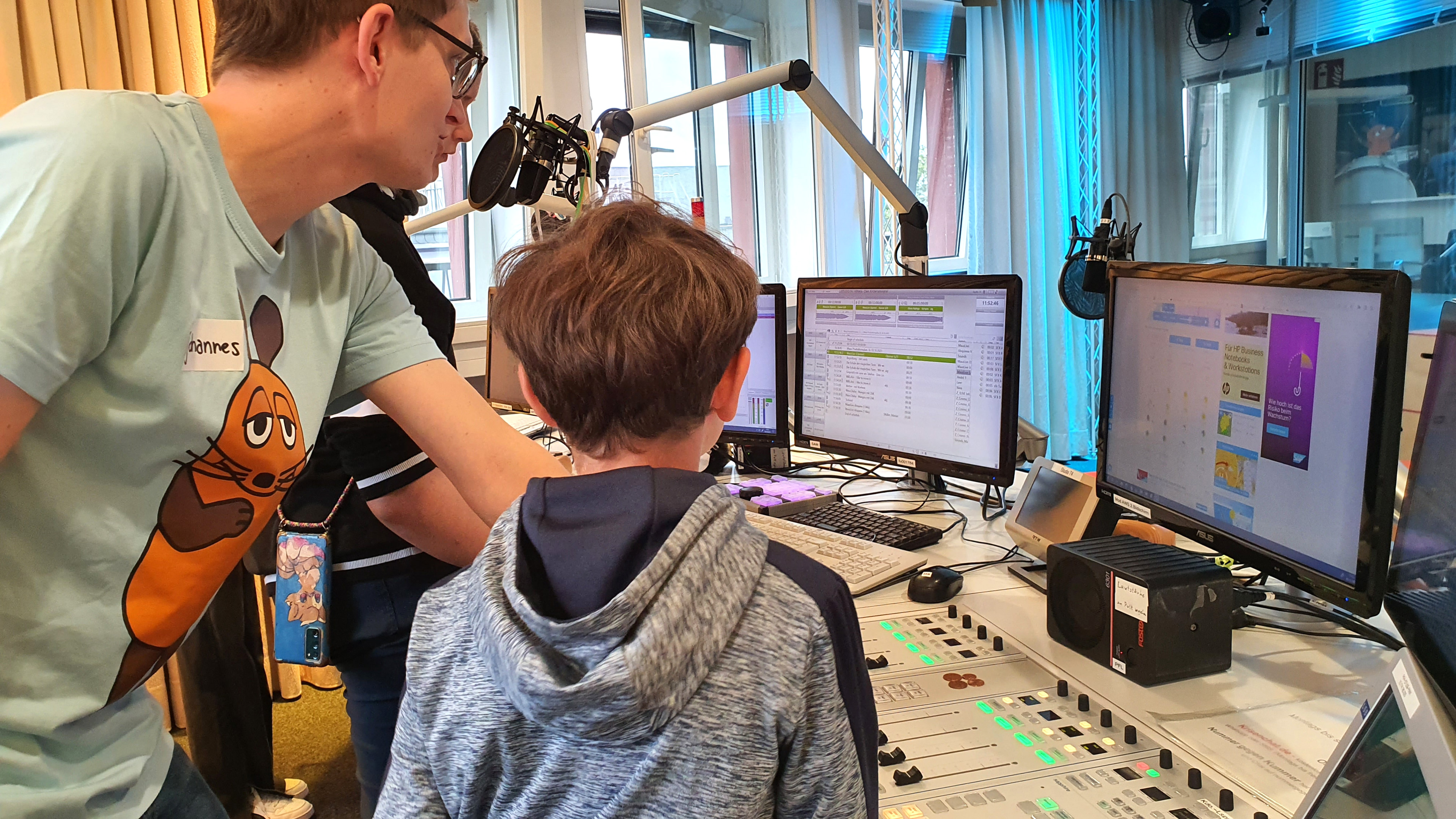 MausLive-Moderator erklärt Kinder das Sendepult im MausLive-Studio