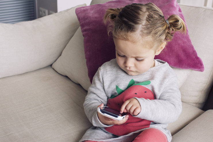 Mädchen sitzt auf dem Sofa und tippt auf ein Smartphone