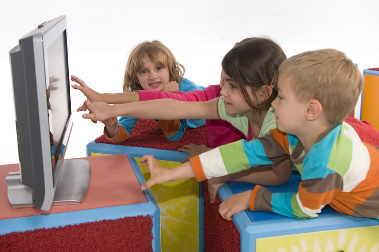 Kinder sitzen vor dem Fernseher und zeigen mit ihren Fingern auf den Bildschirm