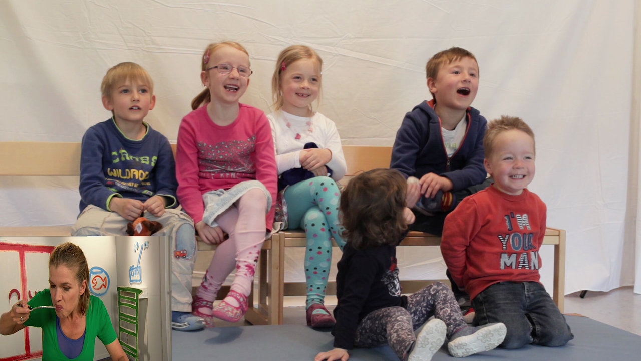 Sechs Kindergartenkinder auf Stühlen schauen in eine Richtung, lachen und rufen