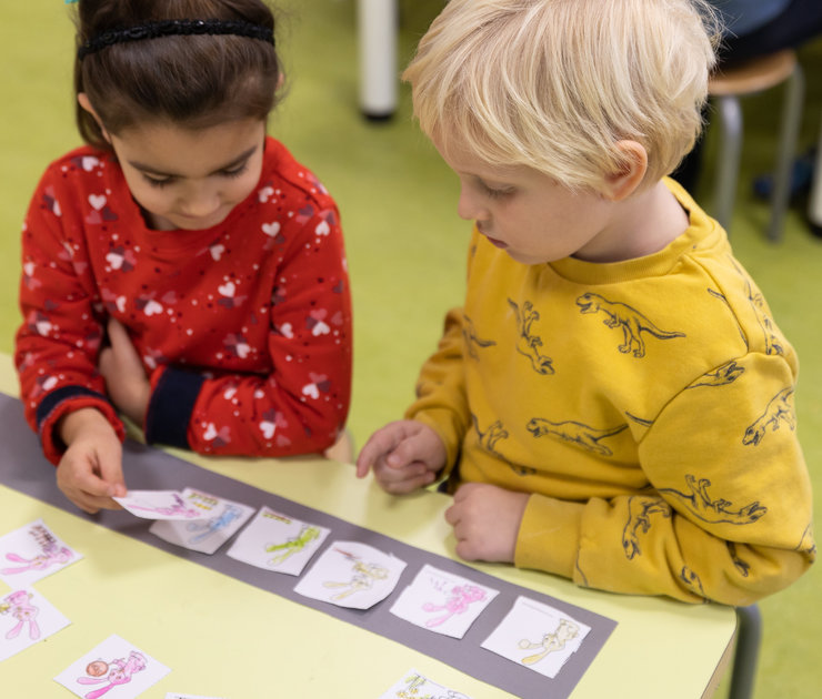 Zwei Kinder sortieren kleine Papierquadrate mit dem Hasen darauf