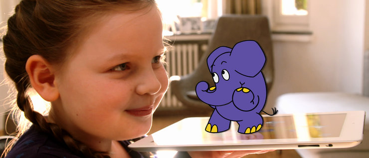 Ein Mädchen hält ein Tablet in der Hand, auf dem der Elefant steht.