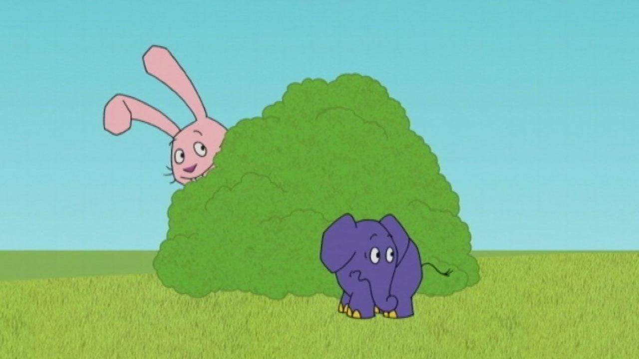 Der Elefant steht vor einem Busch und der Hase schaut hinter dem Busch hervor