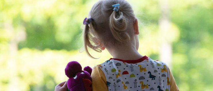 Mädchen von hinten mit Teddy im Arm