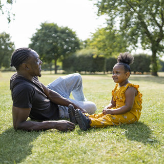 Vater und Tochter sitzen im Park und reden.