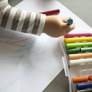 Ein Kinderarm, der einen Stift in der Hand hat und etwas malt.