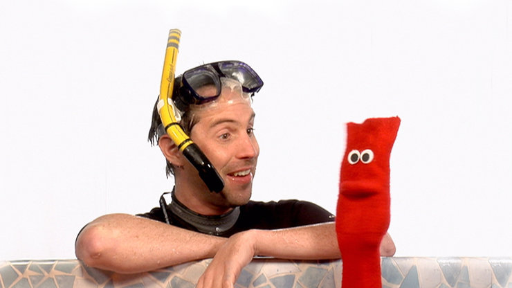 Ein Mann mit Schnorchel und Taucherbrille neben einer roten Socke mit Augen