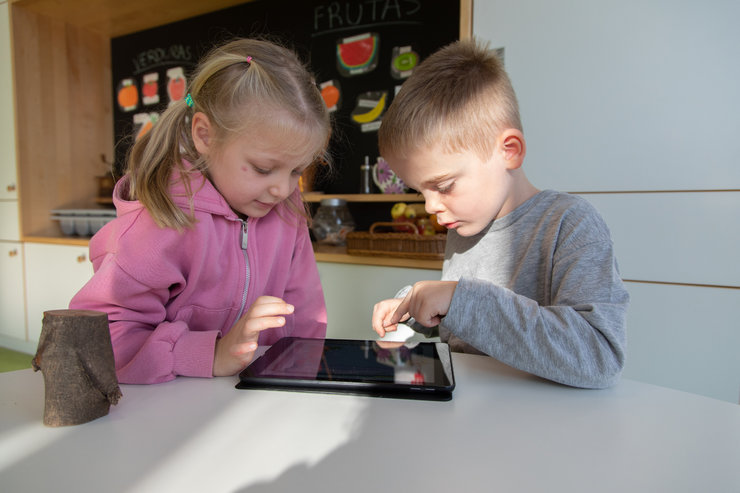 Zwei Kinder tippen auf einem Tablet herum