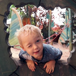 Ein Junge auf dem Spielplatz schaut zwinkernd in die Kamera