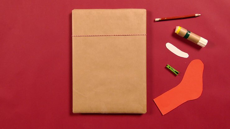 rechteckiges Paket, Klebestift, Stift, Wäscheklammer, rote Socke aus Karton