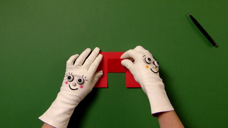Zwei Hände mit Handschuhen klappen ein Stück rotes Papier um