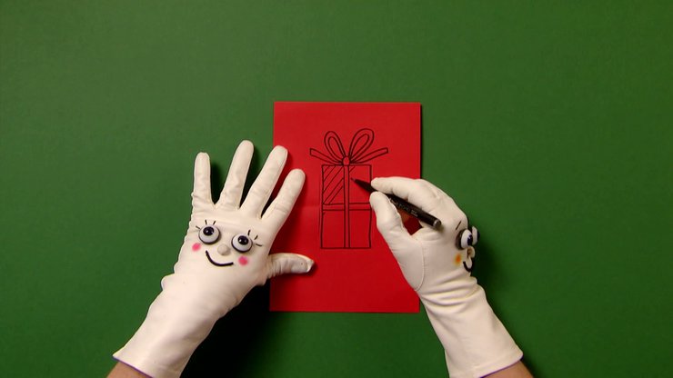 Zwei Hände mit Handschuhen malen ein Geschenk in die rote Karte