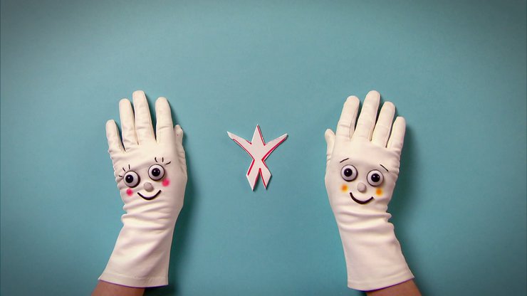 Zwei Hände mit Handschuhen neben dem ausgeschnittenen Stück Papier