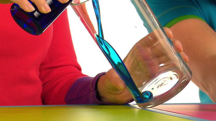 Tanja gießt den blauen Sirup in das Glas.