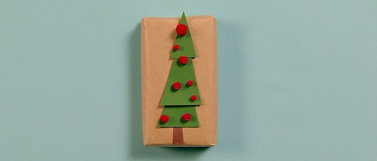 Ein grüner Weihnachtsbaum mit roten Pompons auf Karton