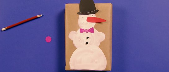 gemalter Schneemann auf braunem Packpapier-Paket auf lila Grund