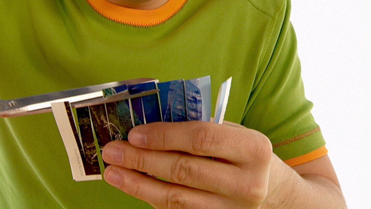 André schneidet mit einer Schere eine Postkarte zu