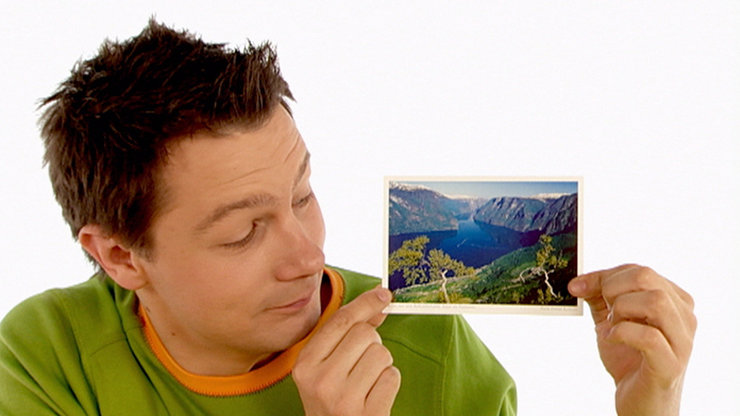 André zeigt eine Postkarte mit Bergseemotiv