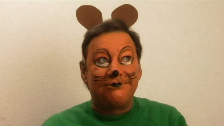 Christoph ist mit orangefarbener Schminkfarbe im Gesicht als Maus angemalt.