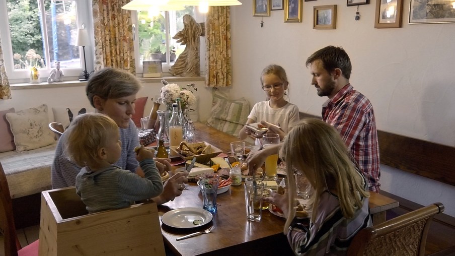 Familie mit 3 Kindern sitzt zu Hause beim Essen an einem Tisch 