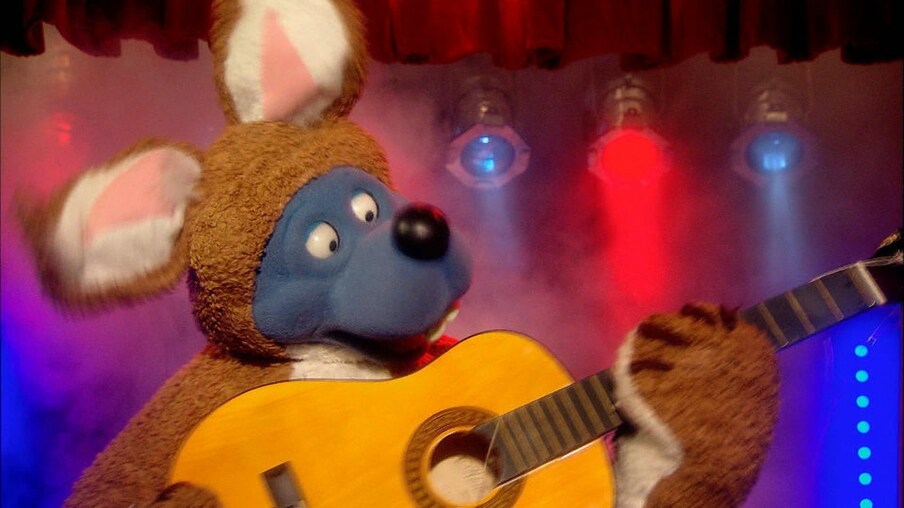Käpt'n Blaubär spielt Gitarre. Er trägt ein Osterhasenkostüm.