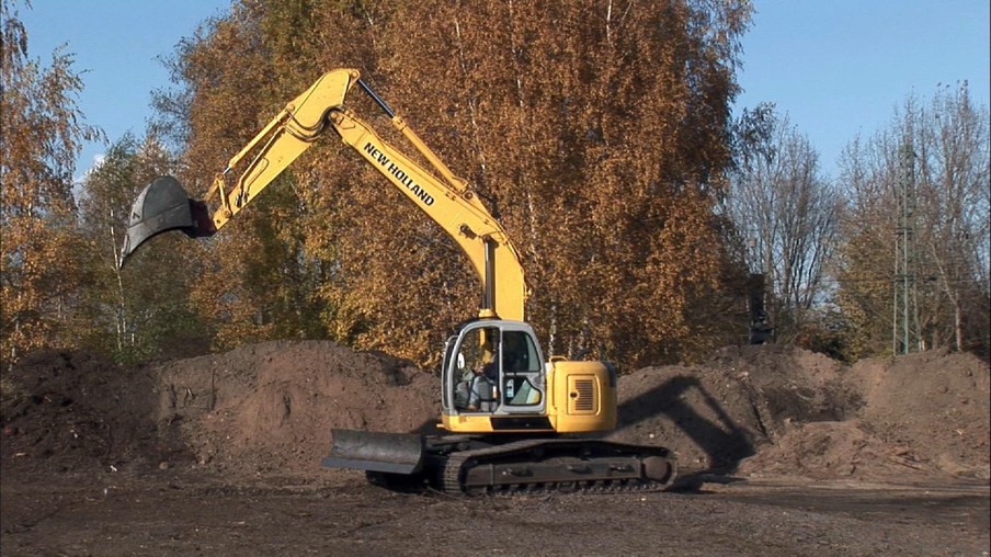 Ein gelber Bagger, der in brauner Erde steht