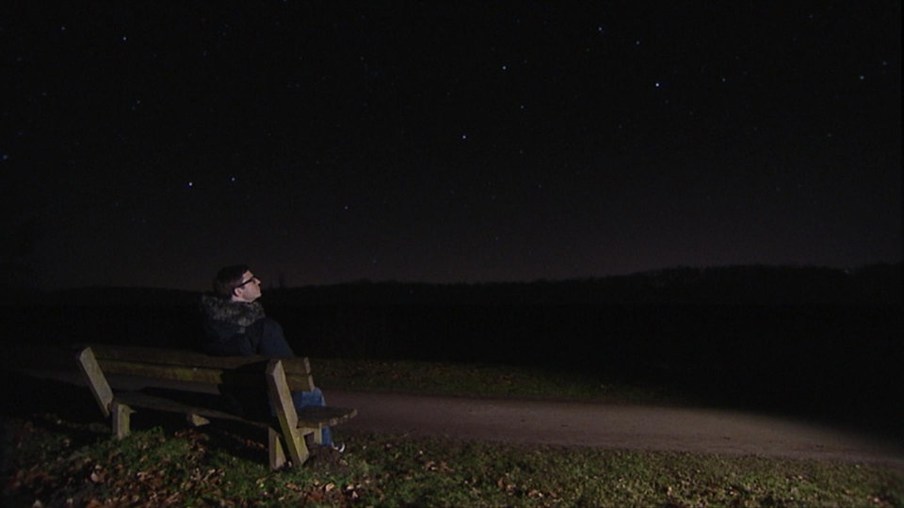 Ralph sitzt auf einer Bank und schaut in den Sternenhimmel