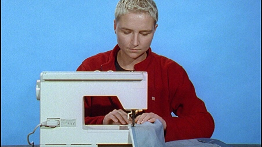 Frau mit einem roten Pullover näht an einer Nähmaschine 