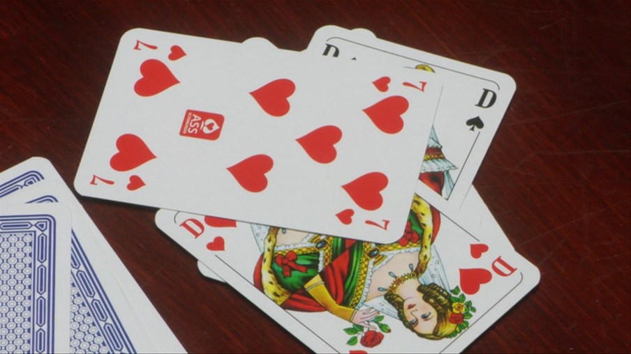 Spielkarten liegen übereinander, oben liegt die Herz 7, darunter zwei Damen