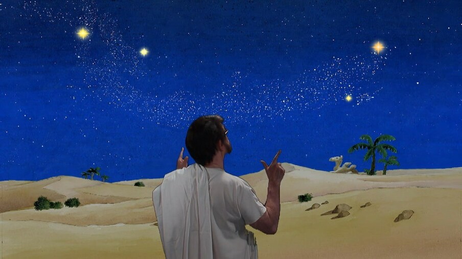 Mann steht in der Wüste und zeigt auf den Sternenhimmel