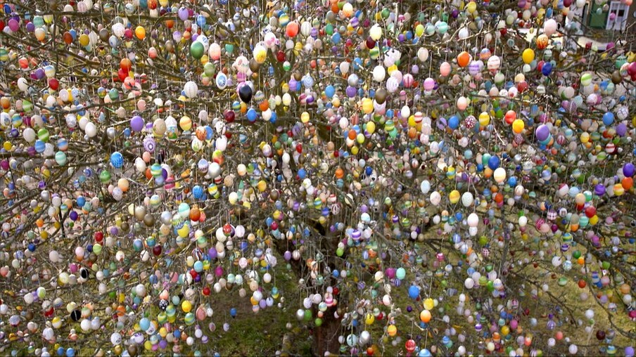 Andre, die Maus, und ein Ehepaar stehen neben einem Baum, der mit Ostereiern geschmückt ist