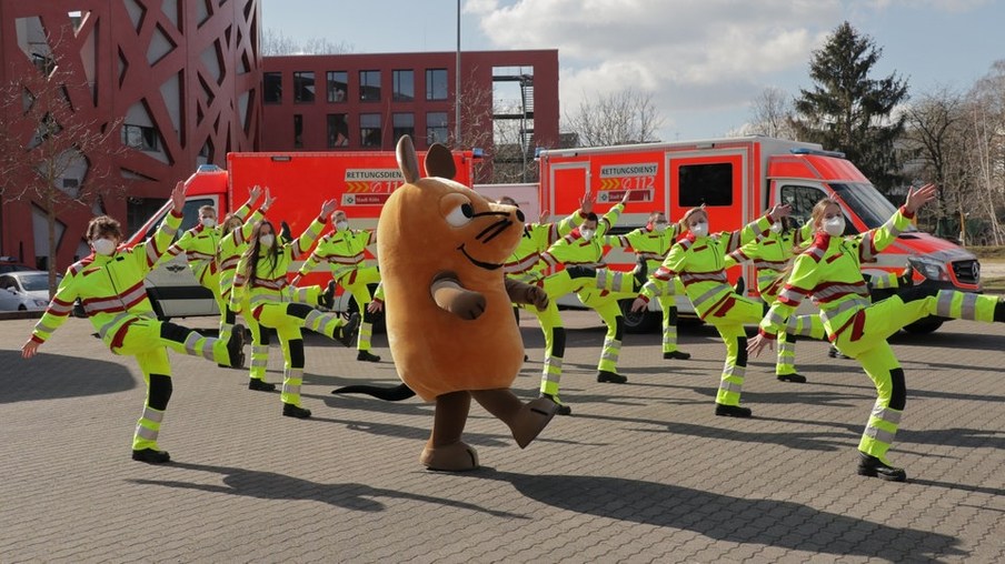 Die Maus tanzt gemeinsam mit Rettungssanitäterinnen und Rettungssanitätern