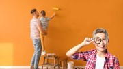 Familie streicht Wand mit oranger Farbe an.